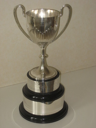 A silver cup with two loop handles on a silver and black stand